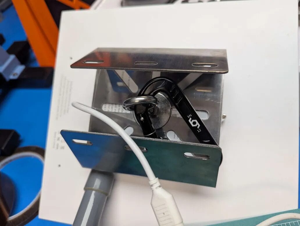 A mounting bracket and hose clamp hold the solar panel to the enclosure.